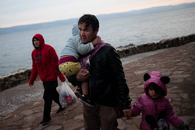 A man holds two children as migrants from Afghanistan arrive on a beach, after crossing part of the Aegean Sea from Turkey to the island of Lesbos