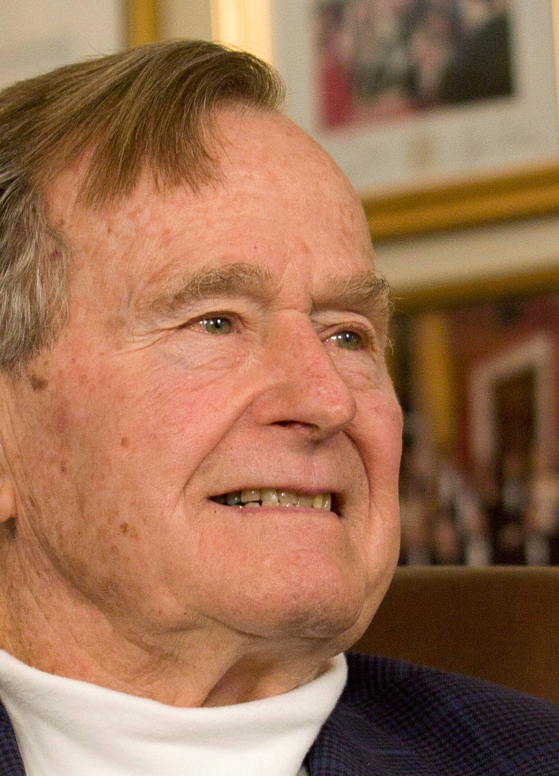 FILE PHOTO: Former President George H.W. Bush smiles as he listens to Republican presidential candidate Mitt Romney speak as he met with Bush to pick up his formal endorsement in Houston