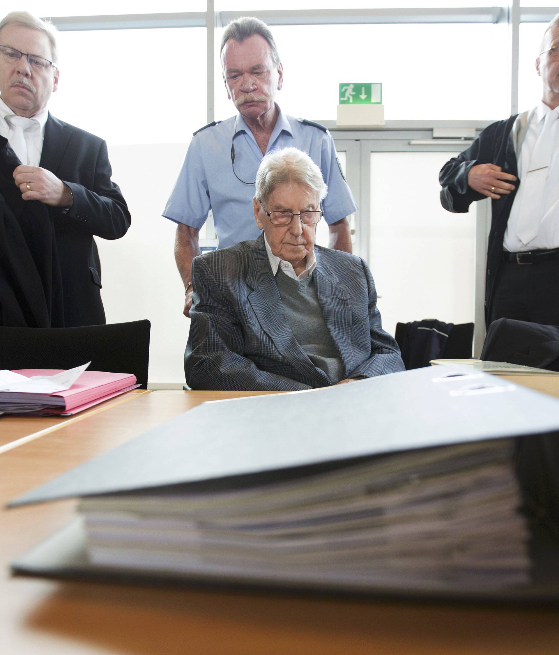 Defendant Hanning, a 94-year-old former guard at Auschwitz death camp, sits in a courtroom as his lawyers Scharmer and Salmen stand next to him before his trial in Detmold