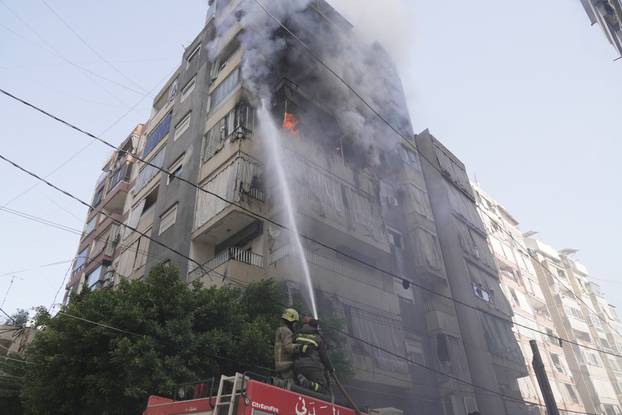 Members of the Lebanese Civil Defence work to extinguish a fire in a building after an Israeli strike on Beirut
