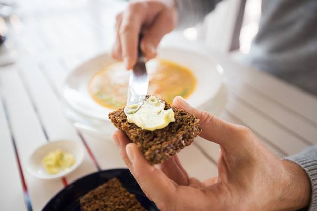 close up of hands applying butter to bread