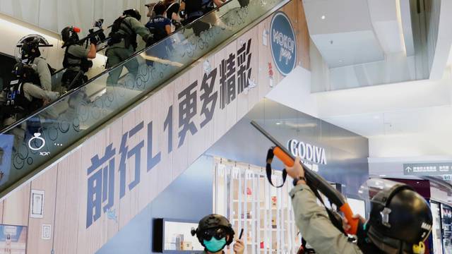 Riot police raise their pepper spray projectile inside a shopping mall as they disperse anti-government protesters during a rally, in Hong Kong