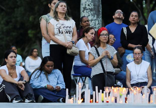 People take part in a candle vigil outside a church to pray for victims of earthquakes, in Valencia