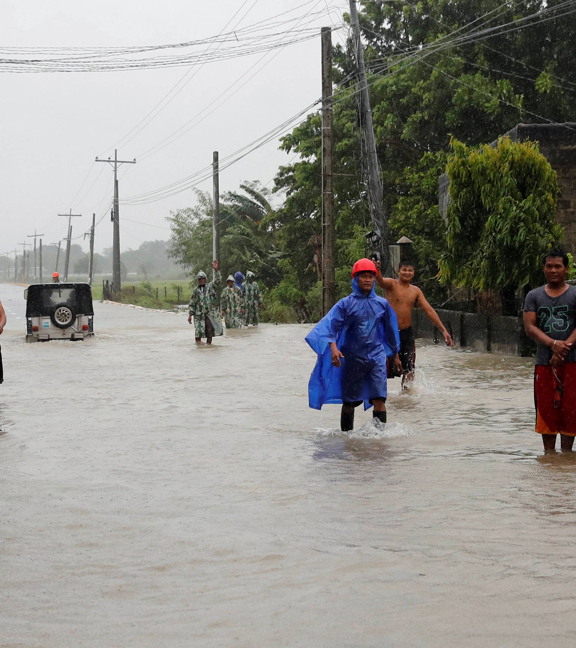 Stranded commuters stand on a partially flooded road after Typhoon Mangkhut hit the main island of Luzon, in Carranglan, Nueva Ecija