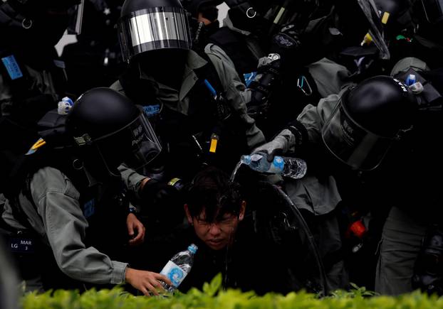 Riot police pour water on the face of anti-government protester who was pepper sprayed while getting detained after an anti-parallel trading protest at Sheung Shui, a border town in Hong Kong