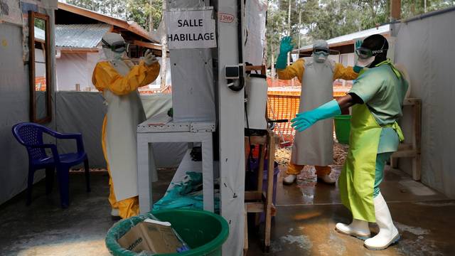 FILE PHOTO: Moise Vaghemi (L), 33, an Ebola survivor who works as a nurse, gets dressed in a protective suit as he prepares to start his shift at an  Ebola treatment centre in Katwa