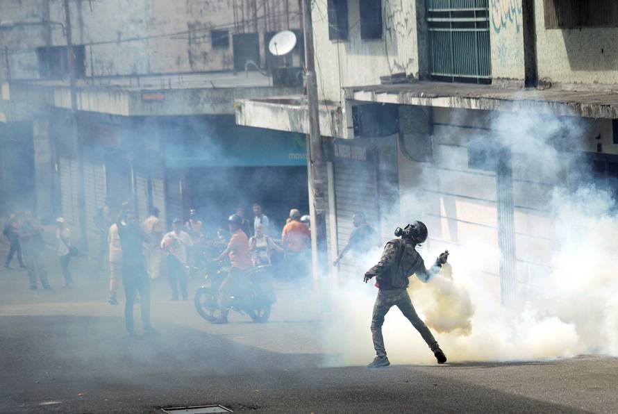 A demonstrator throws back a gas canister while clashing with security forces during a rally in Tachira