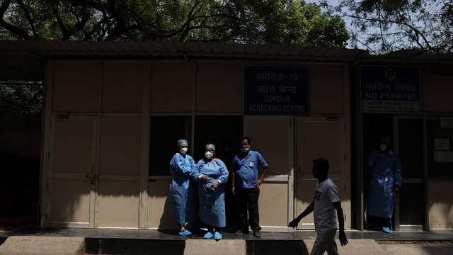 Healthcare workers stand outside a testing centre in a hospital, in New Delhi