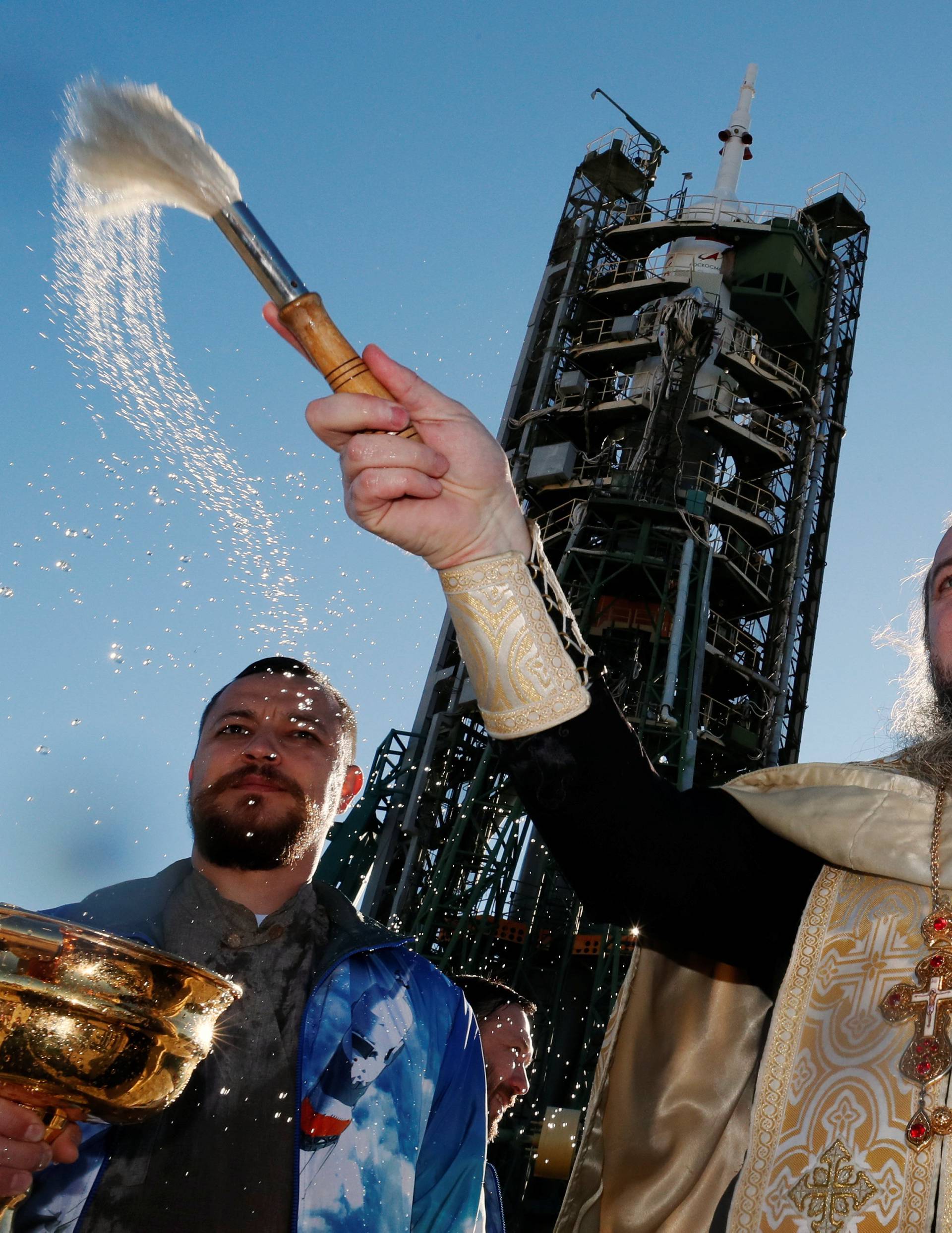 An Orthodox priest conducts a blessing in front of the Soyuz MS-10 spacecraft set on the launchpad at the Baikonur cosmodrome