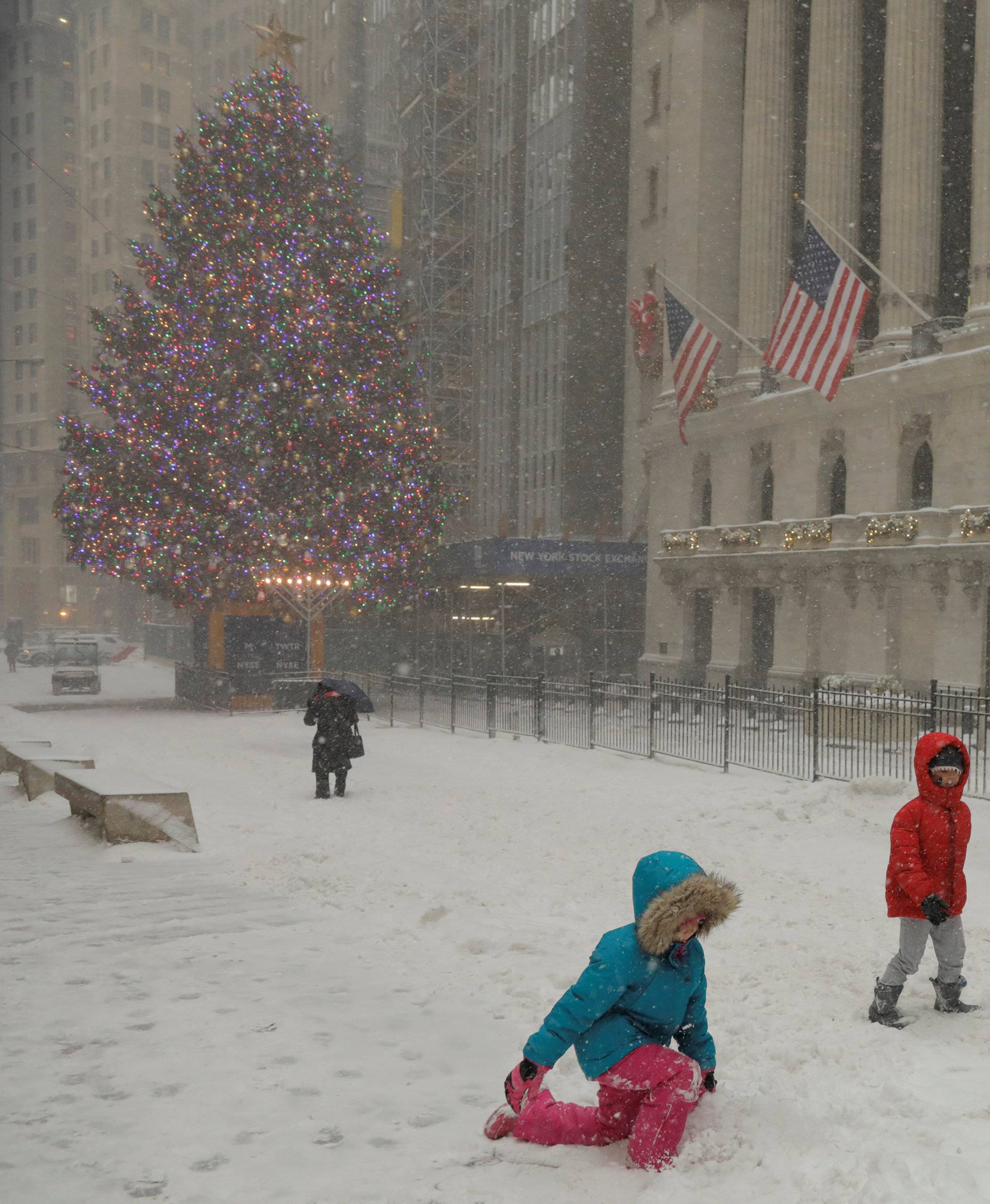 Children play in the snow in front of the New York Stock Exchange during a snowstorm in New York