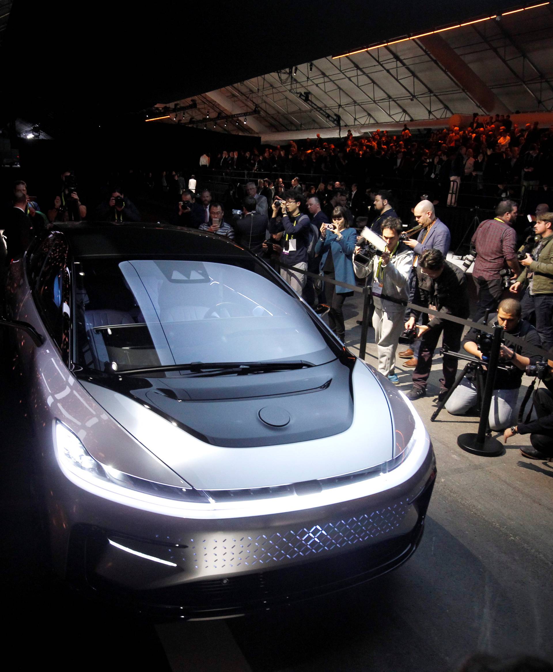 Journalists gather around a Faraday Future FF 91 electric car during an unveiling event at CES in Las Vegas
