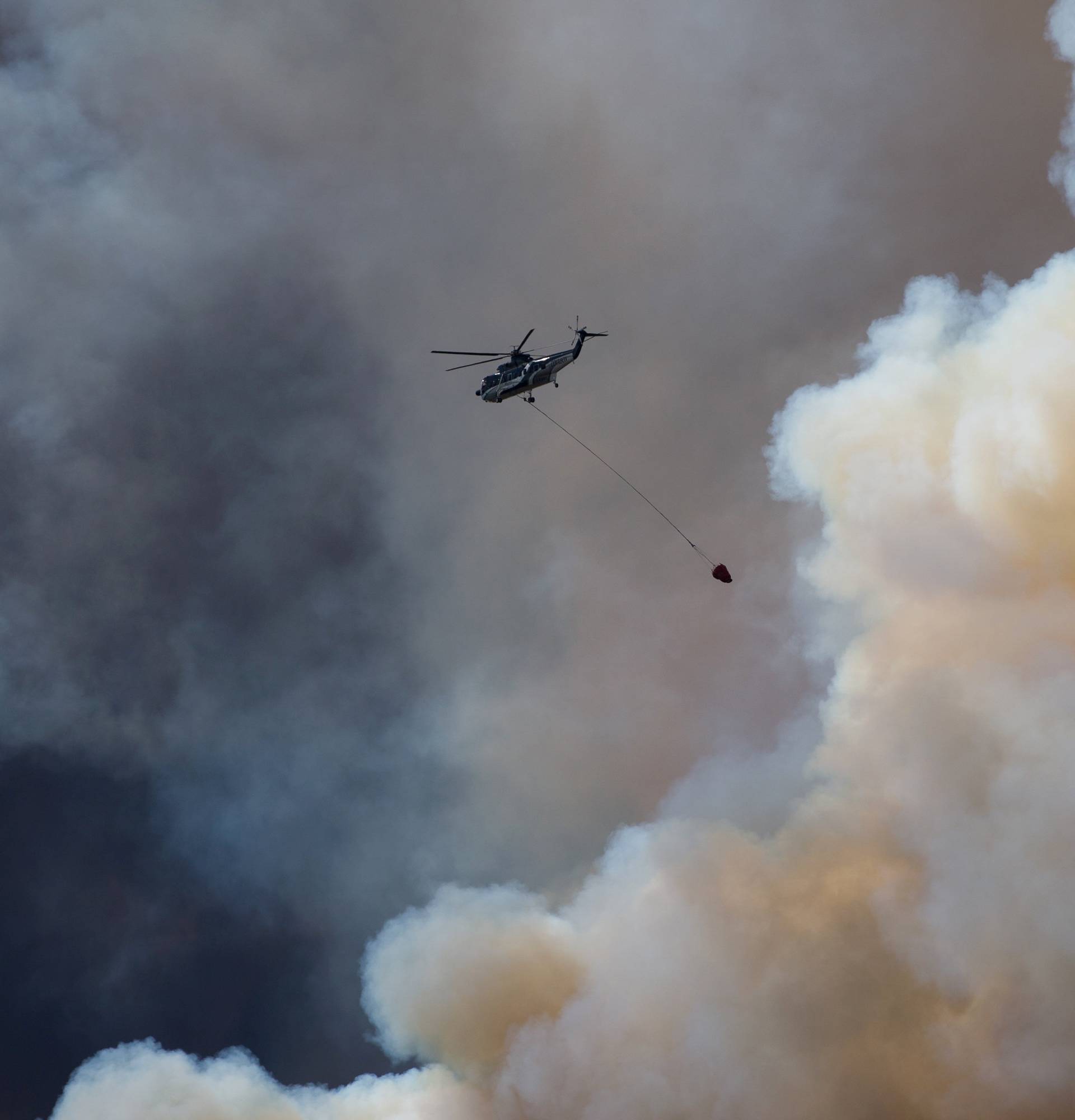 A helicopter flies into thick smoke while battling a major forest fire outside of Fort McMurray