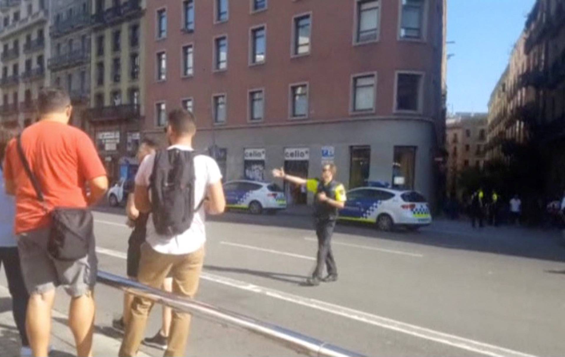 A still image from video shows a police officer ushering people away on a street, after a van crashed into people in the centre of Barcelona