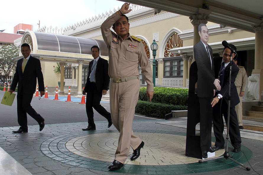 Thailand's Prime Minster Prayuth Chan-ocha speaks to reporters next to a cardboard cut-out of himself at the government house in Bangkok