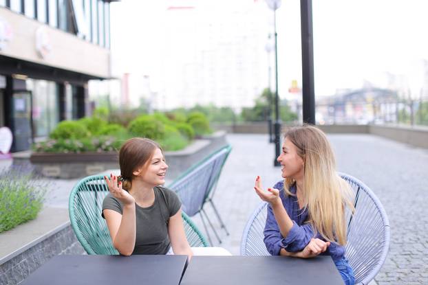 Happy female persons sitting at street cafe outdoors.