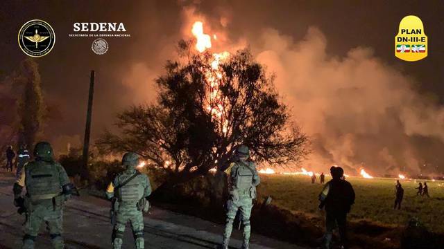 Military personnel watch as flames engulf an area after a ruptured fuel pipeline exploded, in the municipality of Tlahuelilpan, Hidalgo