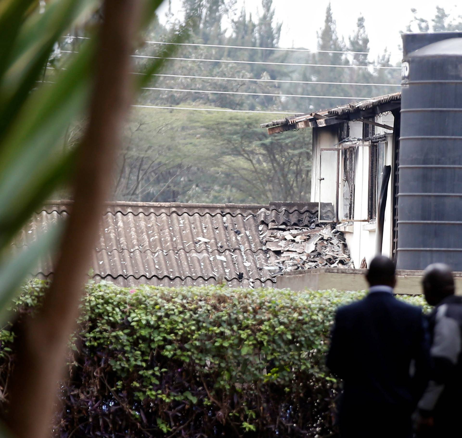 Investigators stand inside a cordon line following a fire that burnt down one dormitory of Moi Girls school in Nairobi