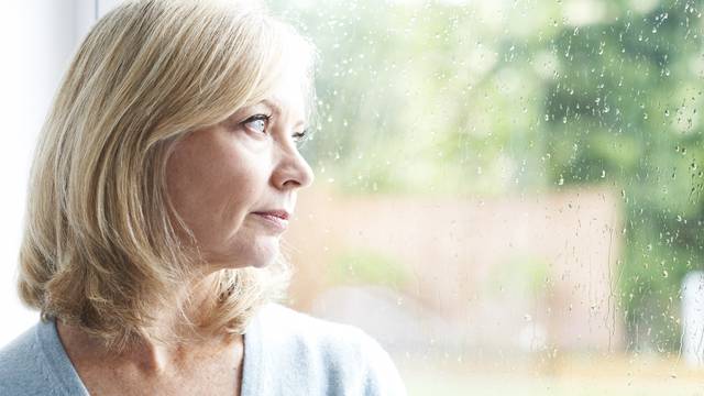 Sad Mature Woman Suffering From Agoraphobia Looking Out Of Windo