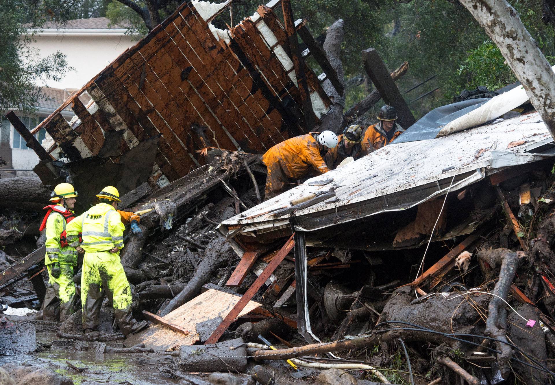 Emergency personnel prepare to rescue a trapped woman inside a collapsed house in Montecito