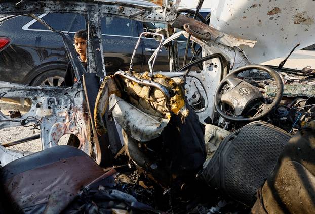Palestinians inspect the site of an Israeli airstrike targeting a police vehicle in the central Gaza Strip