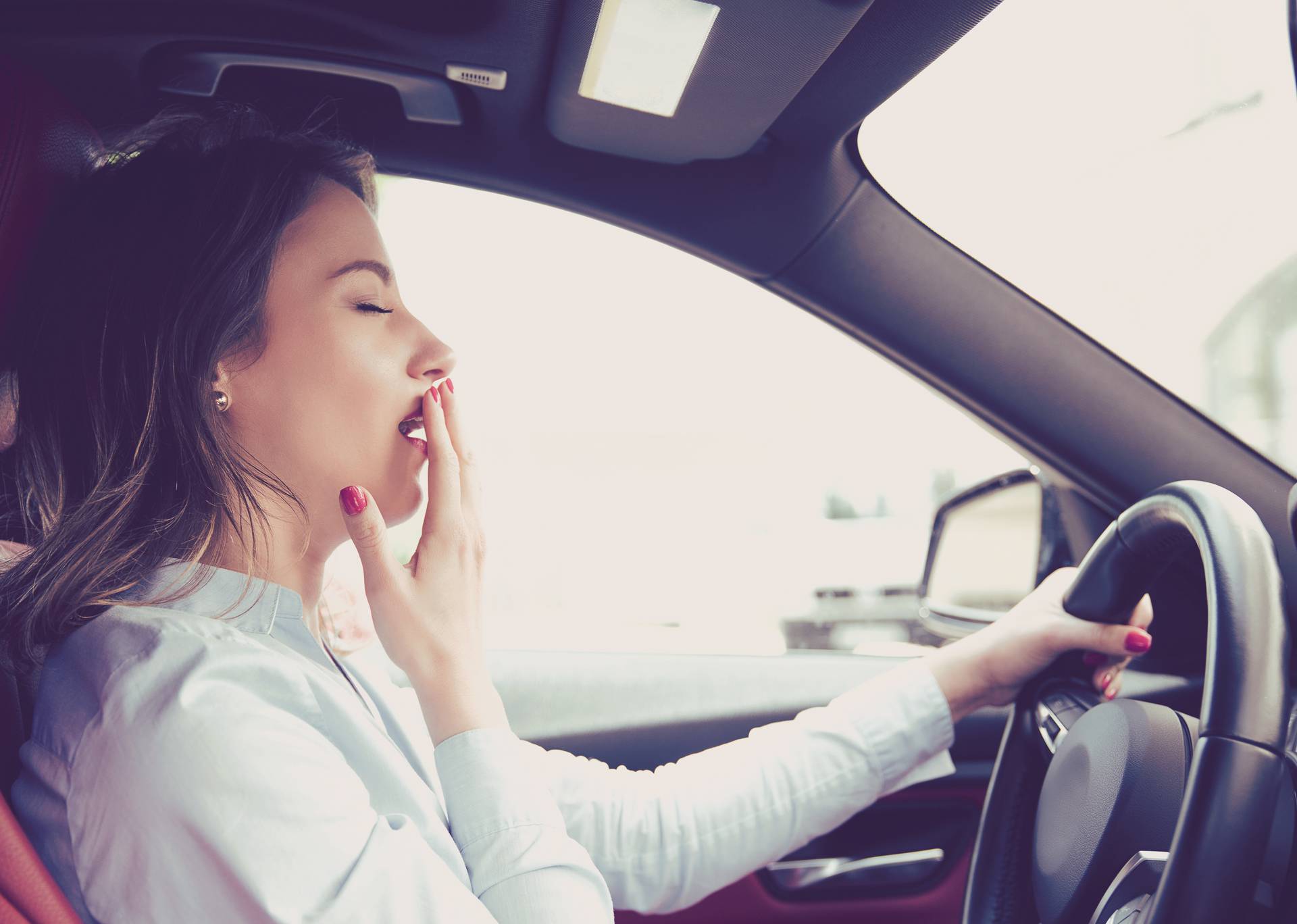 Sleepy woman driving her car after long hour trip isolated street background. Sleep deprivation and accident concept