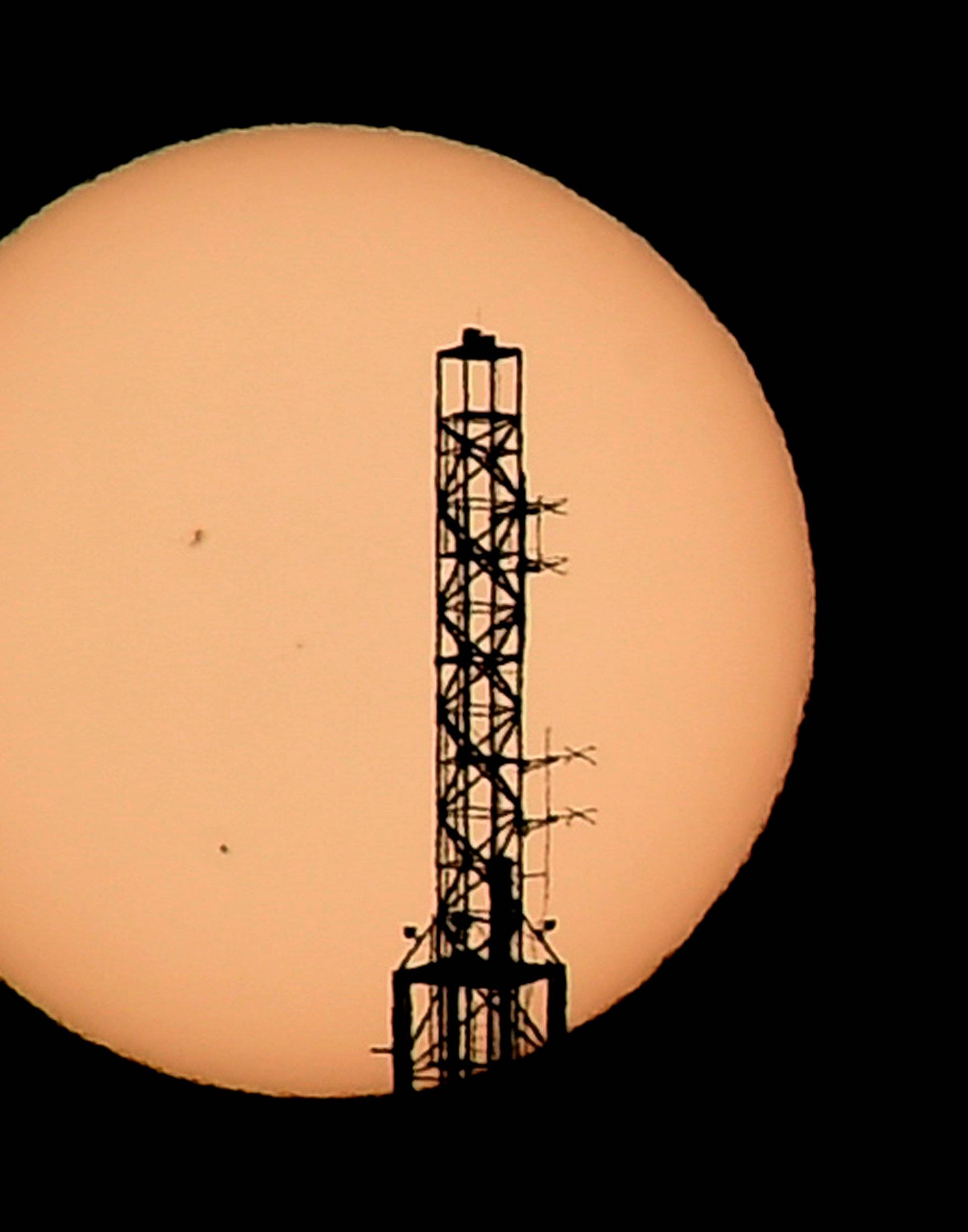 The top of the Stratosphere tower is silhouetted as the planet Mercury is seen, lower left quadrant, transiting across the face of the sun in Las Vegas