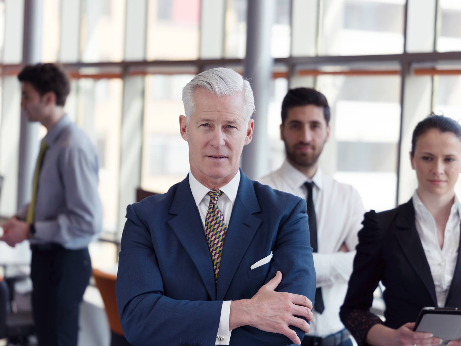 portrait of senior businessman as leader  with staff in backgrou