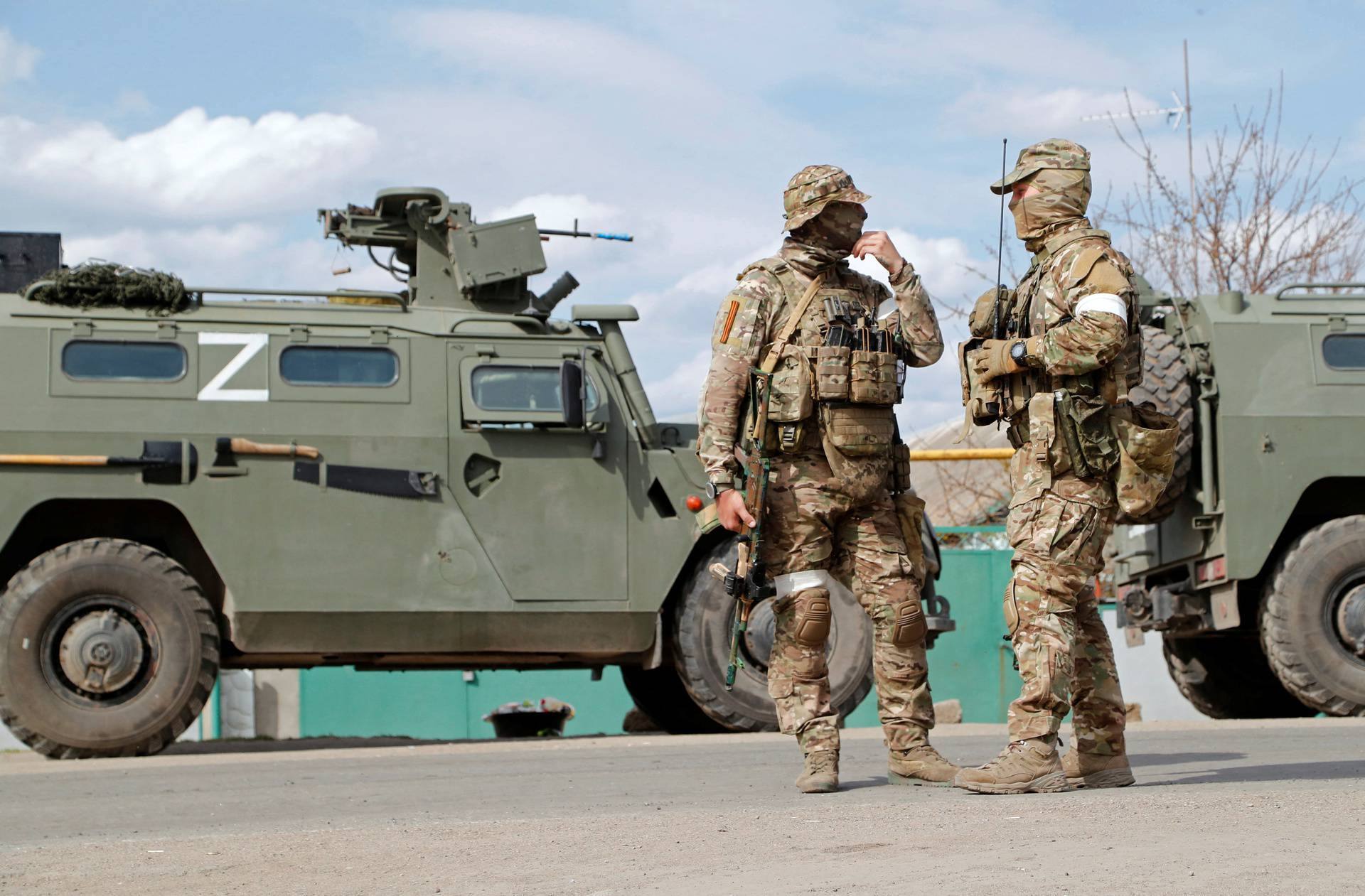 Service members of pro-Russian troops stand guard near a temporary accommodation centre for evacuees in Bezimenne