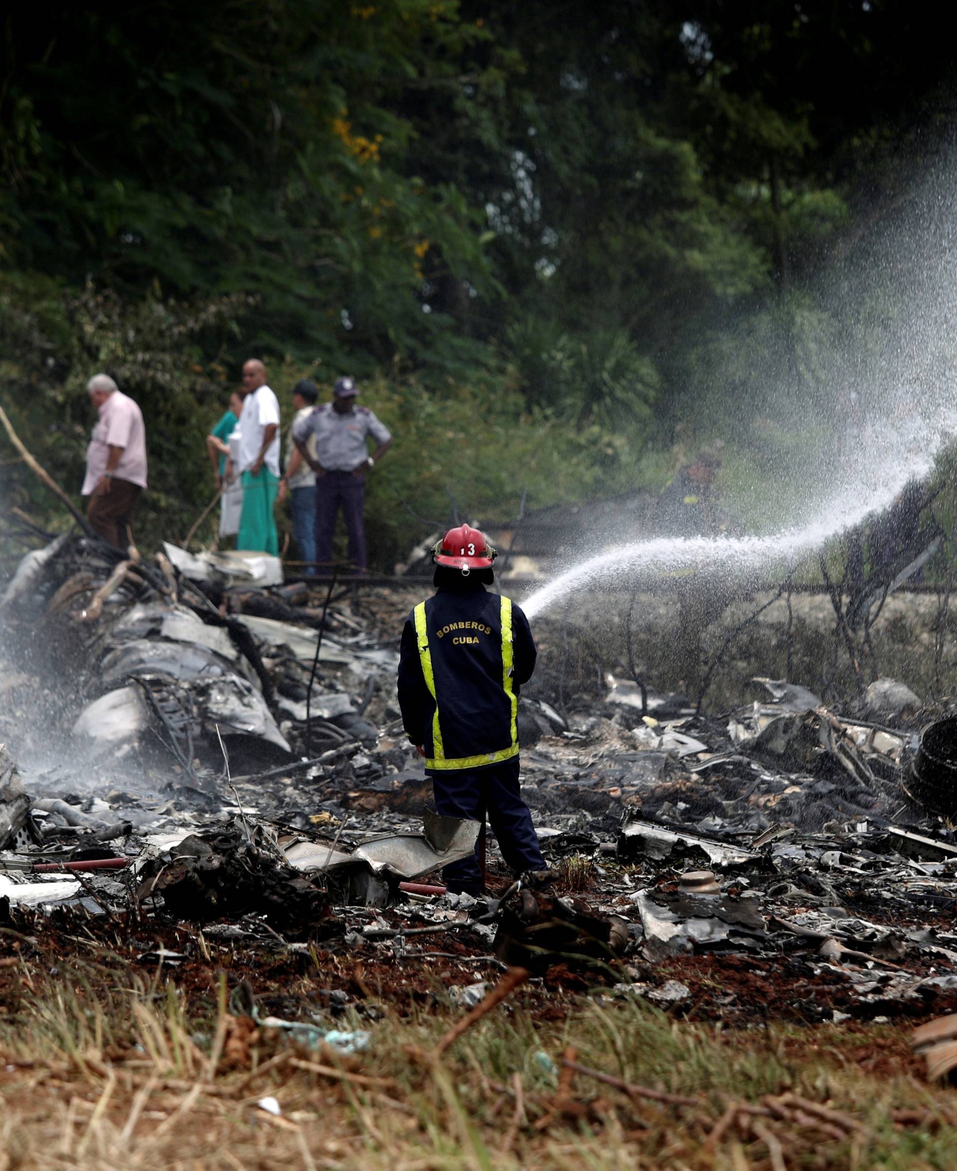 A firefighter works in the wreckage of a Boeing 737 plane that crashed in the agricultural area of Boyeros