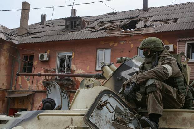 Service members of pro-Russian troops drive an armoured vehicle in Mariupol