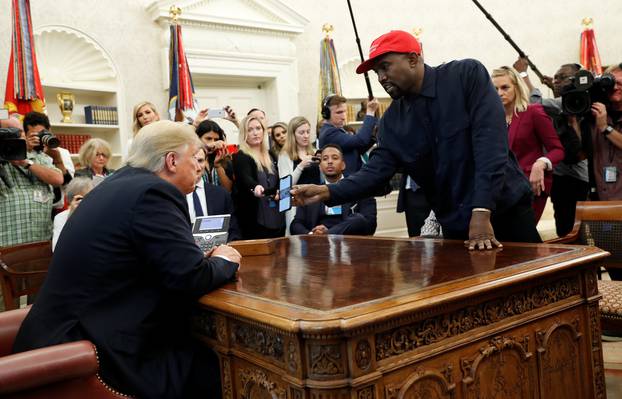 Rapper Kanye West shows President Trump his mobile phone during meeting in the Oval Office at the White House in Washington