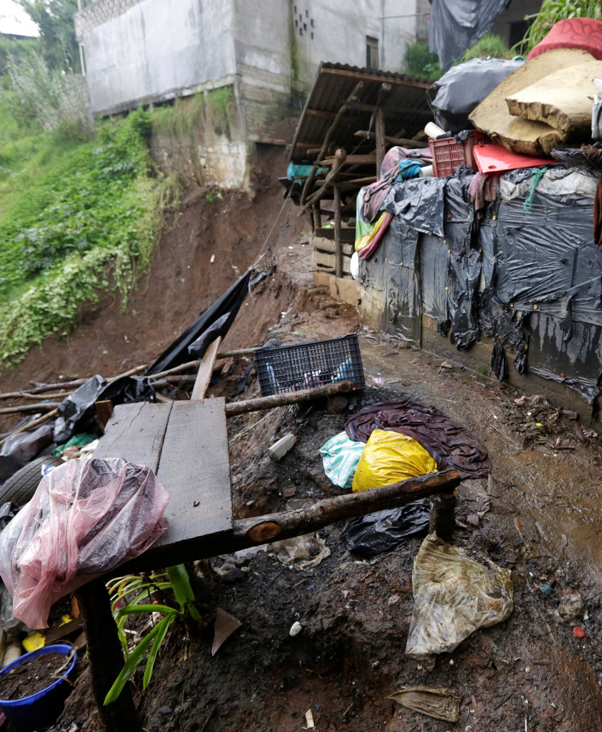 A child shields from the rain as he stands near his house damaged after a mudslide following heavy showers caused by the passing of Tropical Storm Earl, in the town of Huauchinango