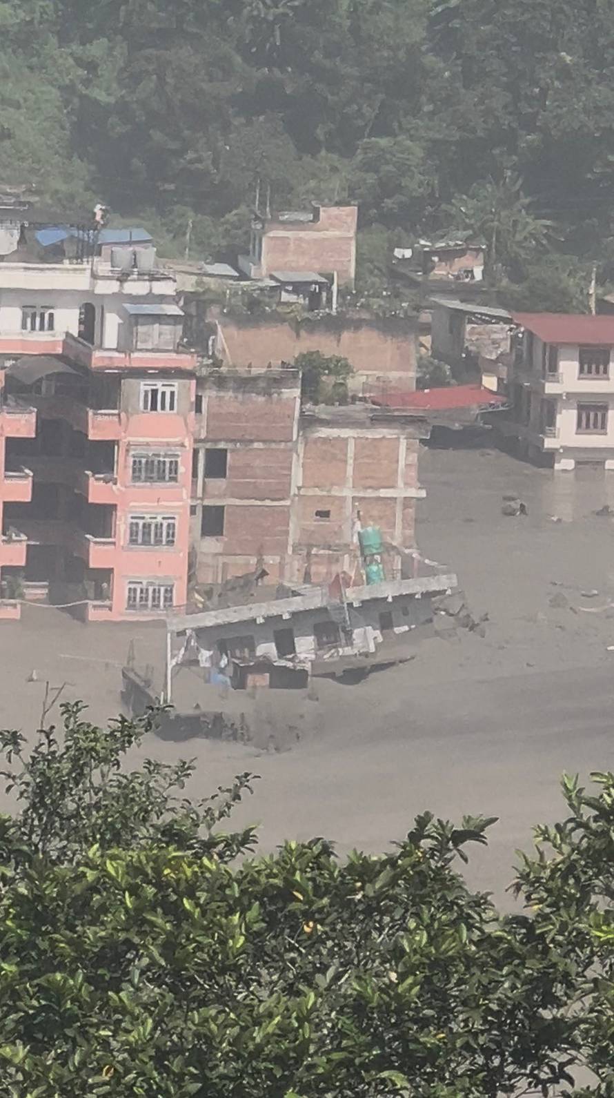 Partially submerged buildings along the riverbank due to a flash flood in Nuwakot district