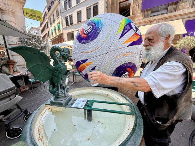 A man fills a glass with water from a public fountain amid a heatwave, in Basel
