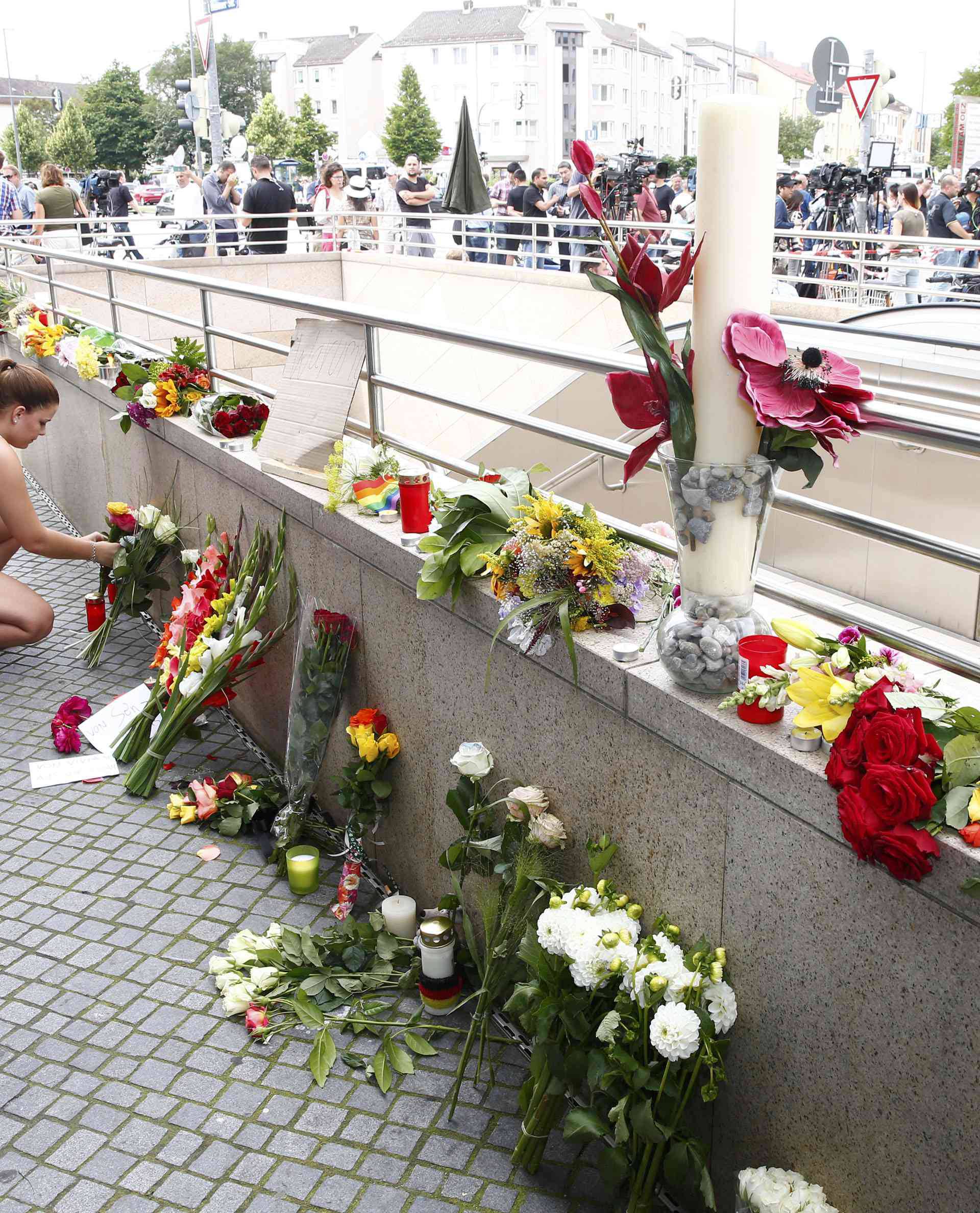 A women places flowers near Olympia shopping mall in Munich