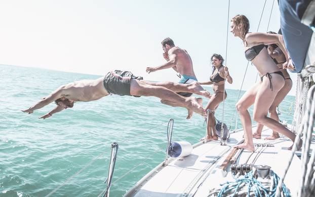 Friends jumping in the water from the boat