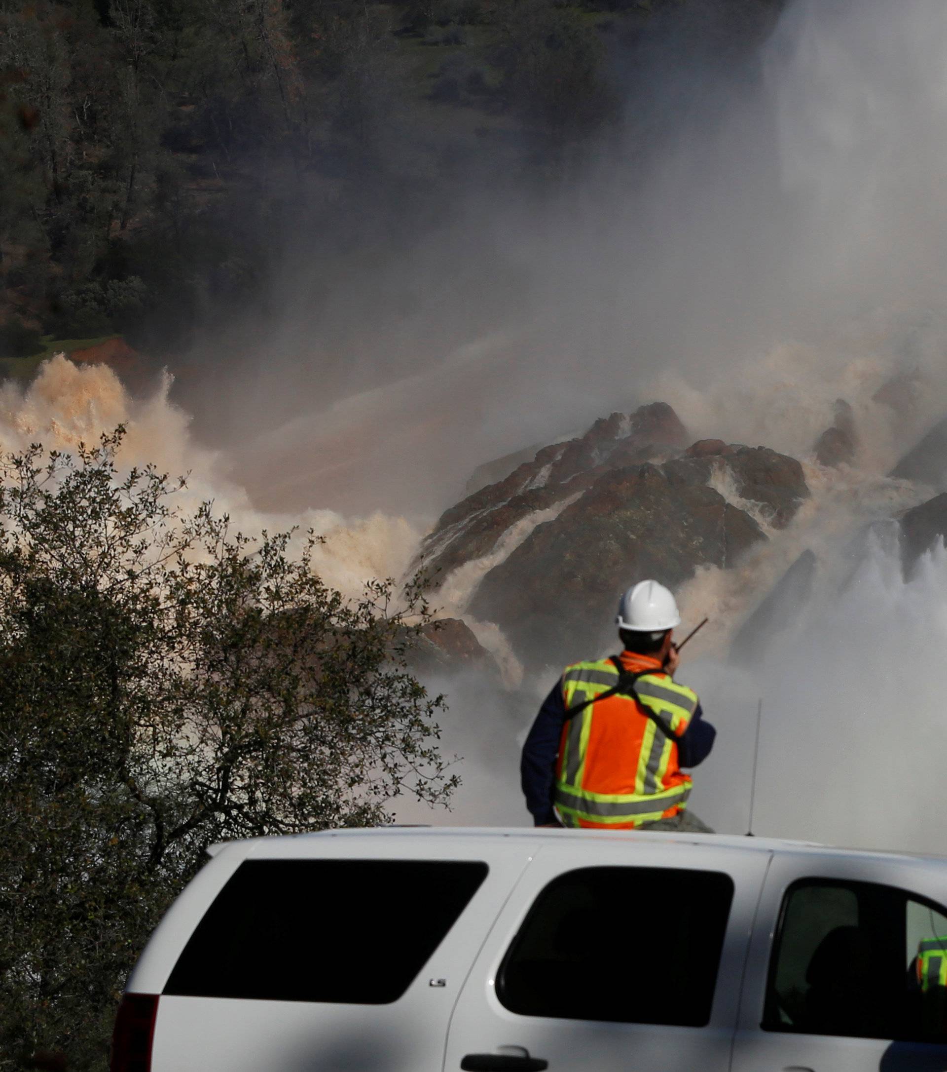 Staff with the California Department of Water Resources watch as water is released from the Lake Oroville Dam after an evacuation was ordered for communities downstream from the dam in Oroville