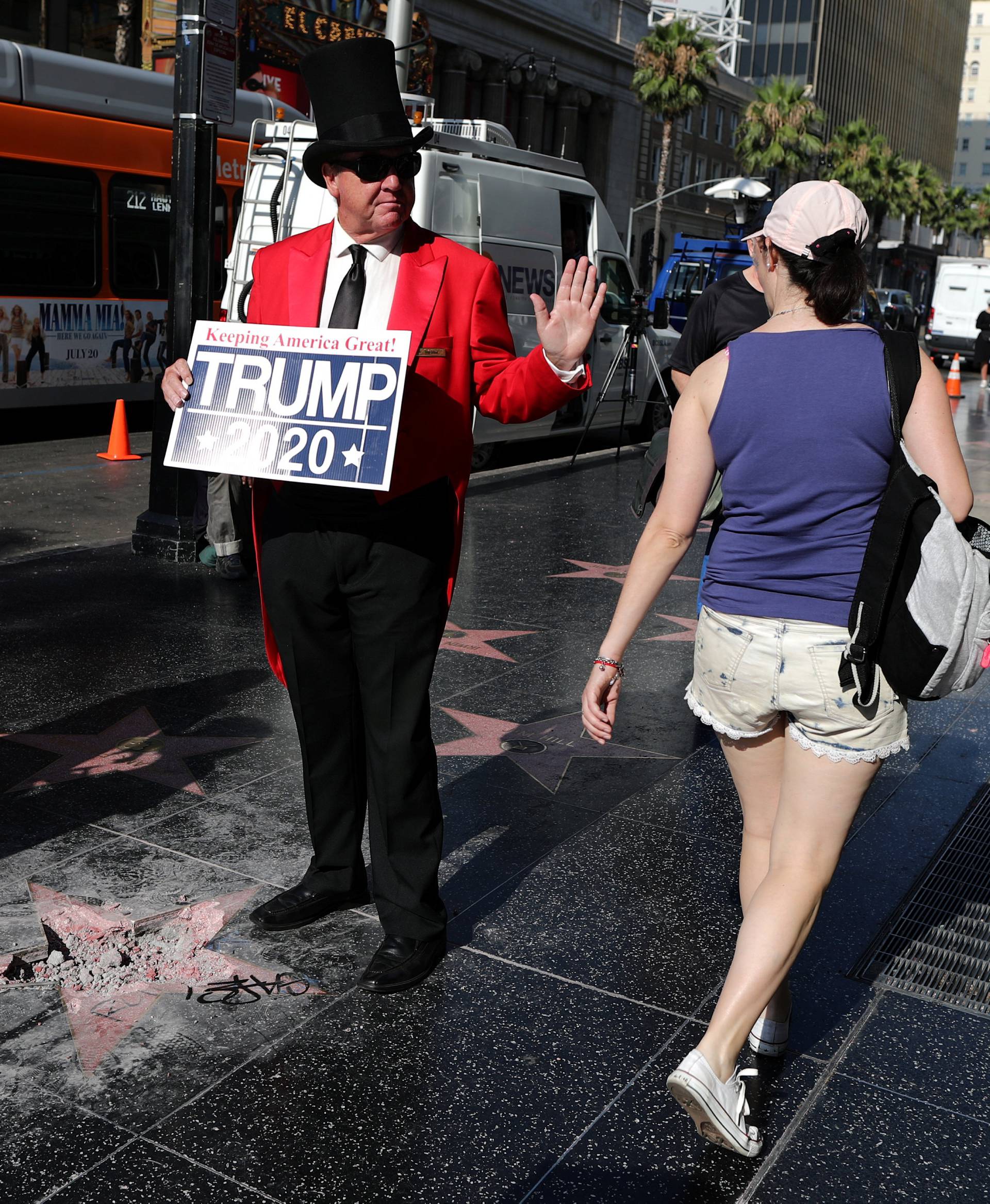 Greg Donovan, 58, waves at a woman walking on Hollywood Boulevard as he stands on President Donald Trump's vandalized star on the Hollywood Walk of Fame in Hollywood, Los Angeles