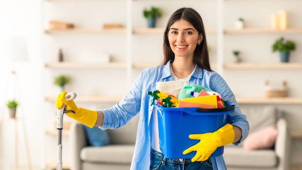 Portrait,Of,Smiling,Millennial,Lady,Holding,Bucket,With,Cleaning,Supplies