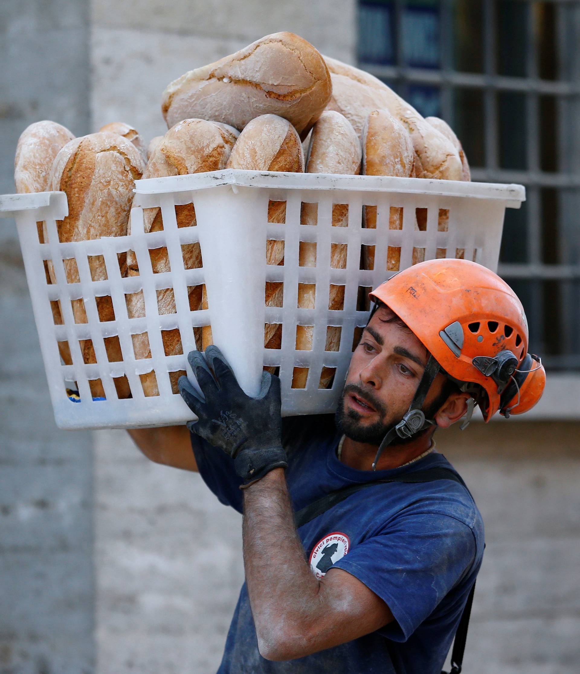 A rescuer carries bread following the earthquake in Amatrice