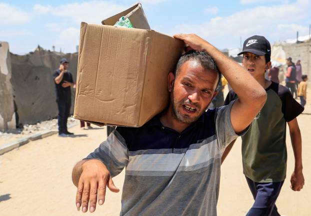 Palestinians carry aid supplies they received from the U.S.-backed Gaza Humanitarian Foundation, in Khan Younis