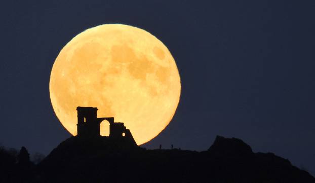 People watch as the Supermoon, known as the Hunter's moon rises over Mow Cop castle in Mow Cop