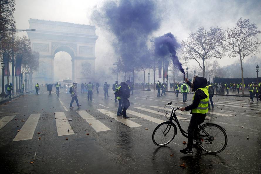 Protesters wearing yellow vests, a symbol of a French drivers' protest against higher diesel taxes, face off with French riot police during clashes at the Place de l'Etoile near the Arc de Triomphe in Paris