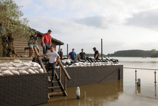 Residents stand next to stacked sandbags by the river Meuse as it continues to rise, in Arcen