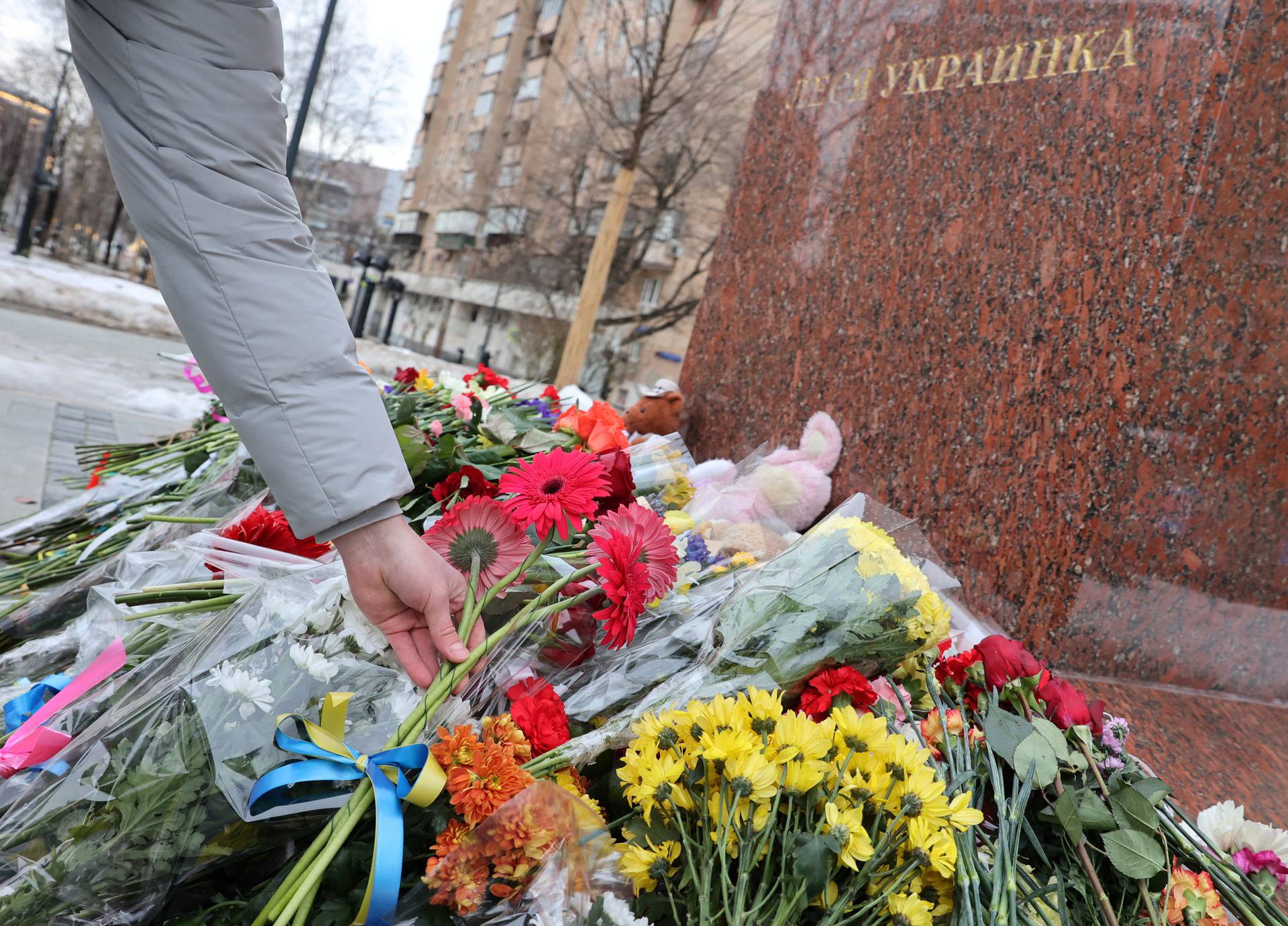 People lay flowers at a monument to Lesya Ukrainka in memory of the victims of the Russian missile strike in Dnipro, in Moscow