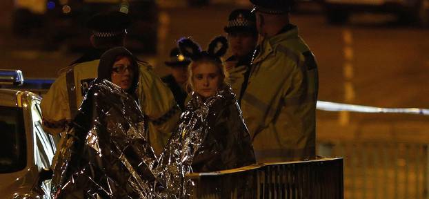 Two women wrapped in thermal blankets look on near the Manchester Arena, where U.S. singer Ariana Grande had been performing, in Manchester, northern England, Britain