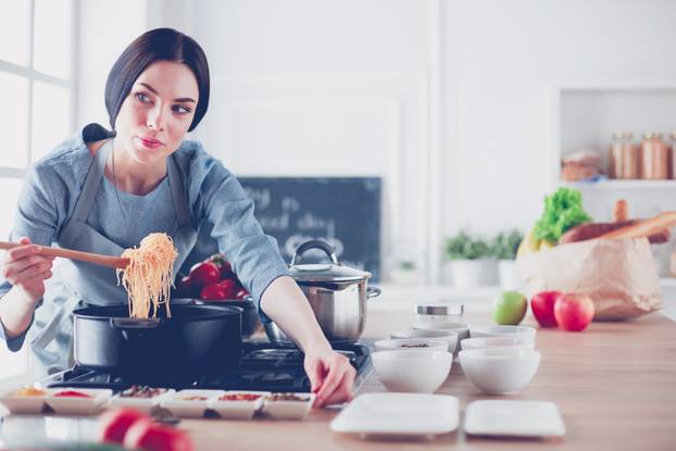 Cooking woman in kitchen with wooden spoon