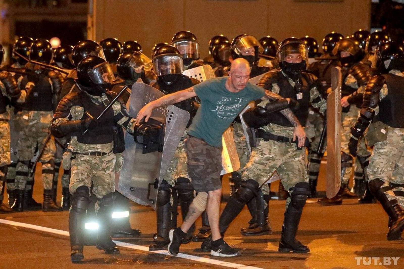 Law enforcement officers escort a man during clashes with opposition supporters after poll closed at presidential election in Minsk