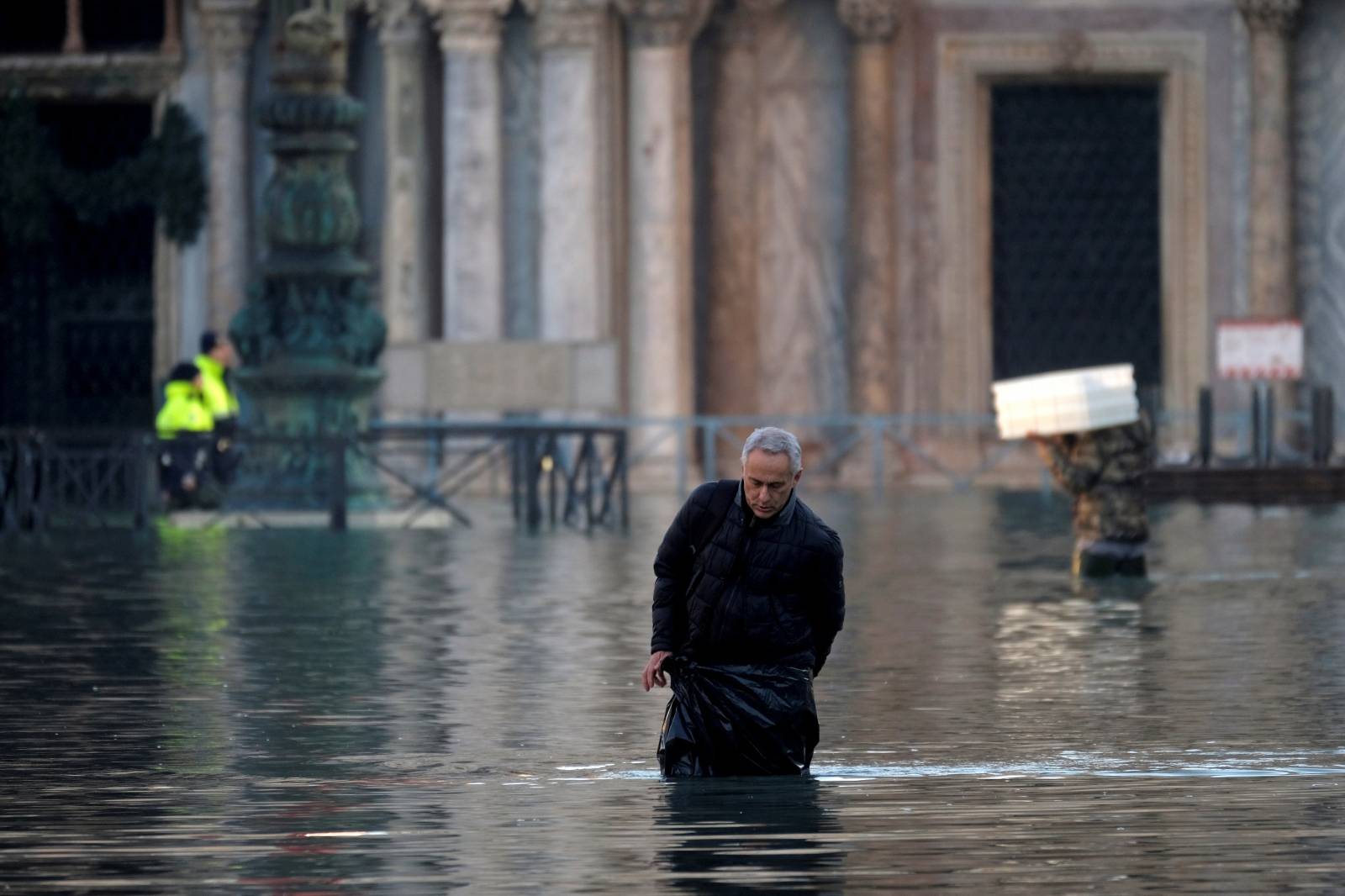 A man wades through a flooded street into St. Mark’s Square during high tide in Venice