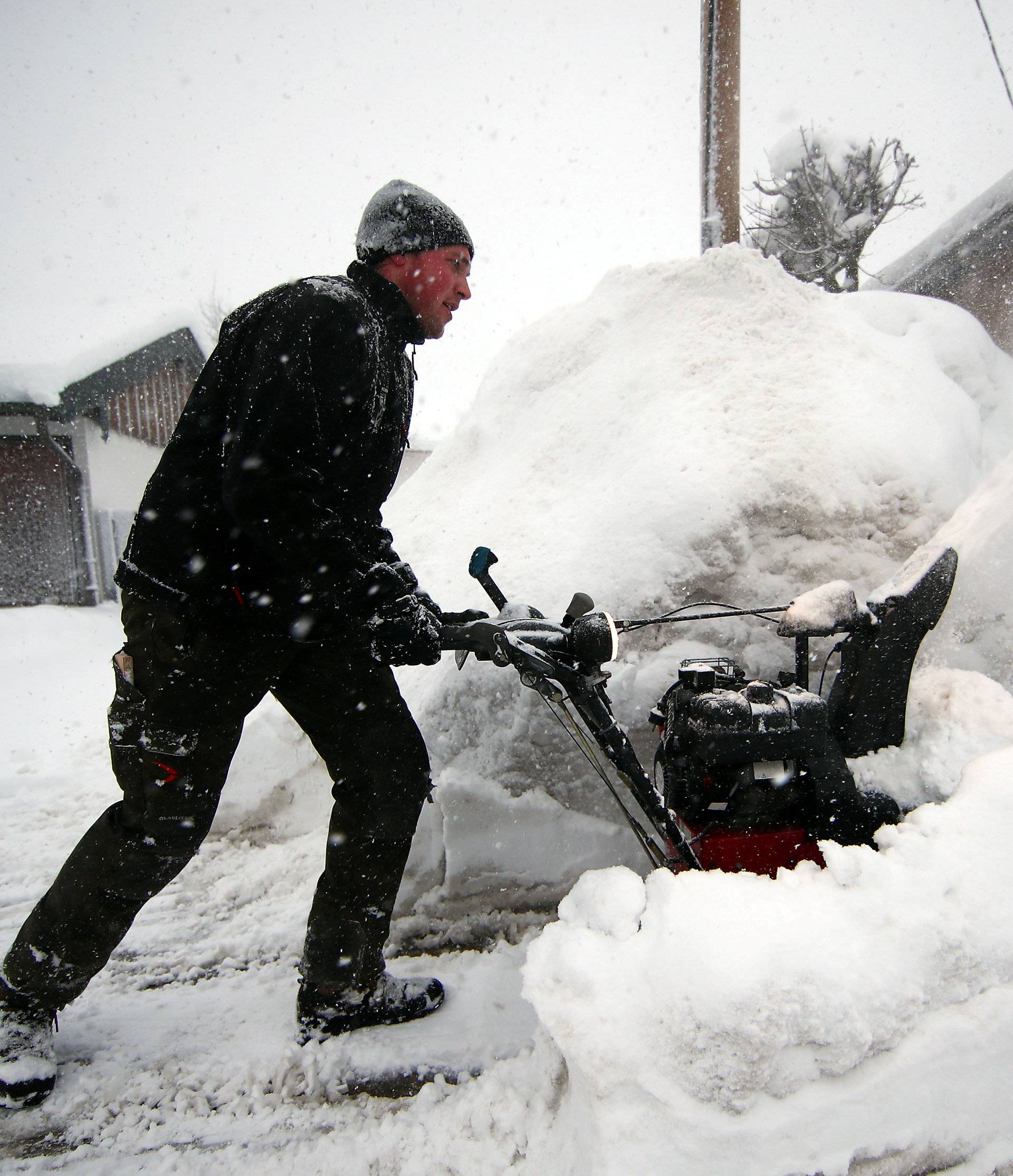 A man uses a snow blower after heavy snowfalls in Schaftlach